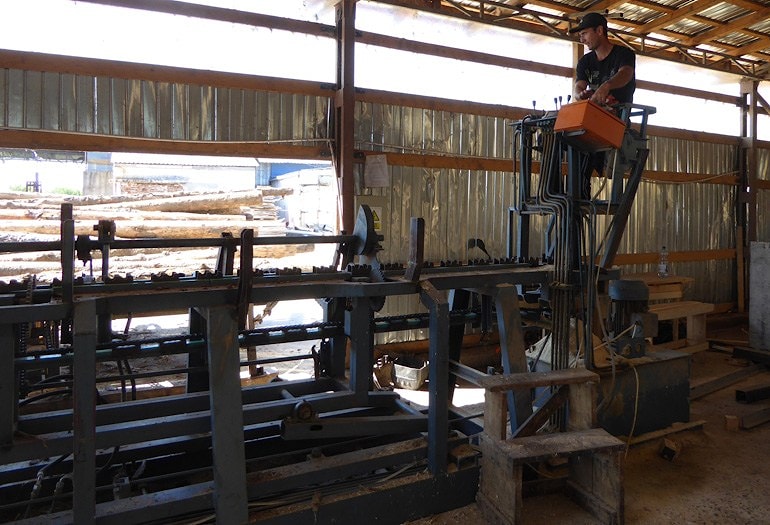 Оператор сдвоенной пилорамы управляет станком с приподнятой платформы