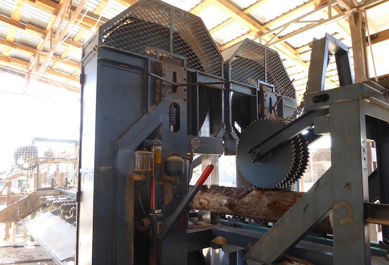 Верхний прижимной валец удерживает бревно в пилящем механизме